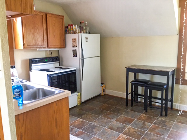 large house kitchen with tile floors, white fridge, and stained wood cabinets