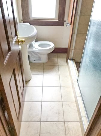 clean bathroom tile floor and wood door with walk in shower