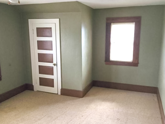 large carpeted bedroom with green walls and dark wood trim